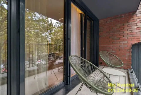 Furnished balcony with glass railing and green view. - image 19