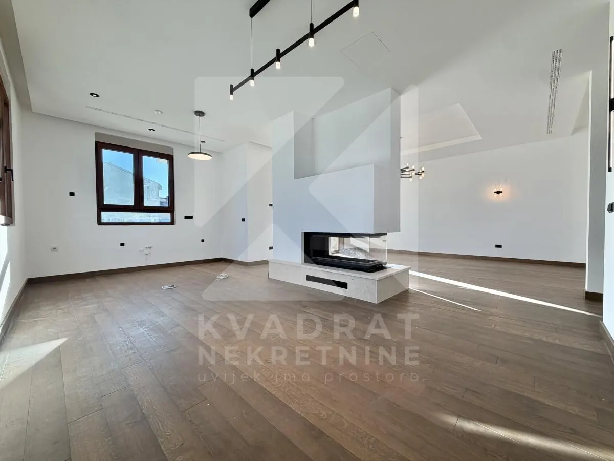 Spacious bright living room with a central modern fireplace and wooden flooring.
