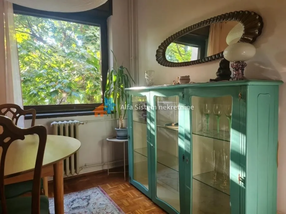 Living room with a wooden dining table and a turquoise display cabinet.