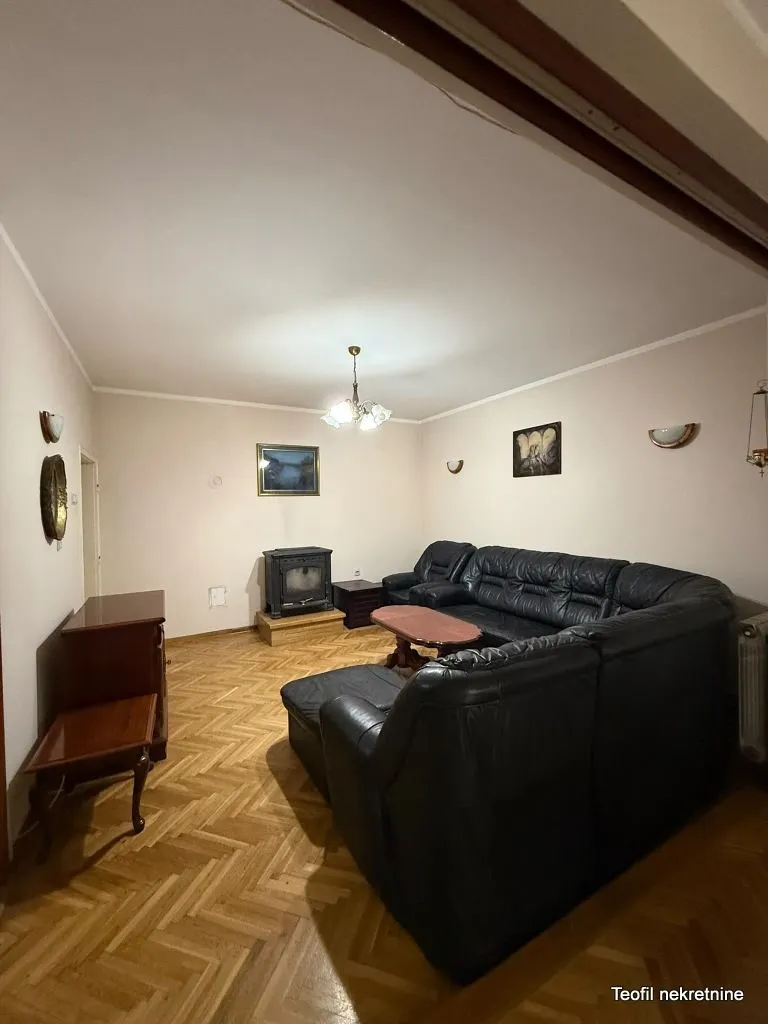 Dnevna soba sa crnom kožnom garniturom i peći na drva.