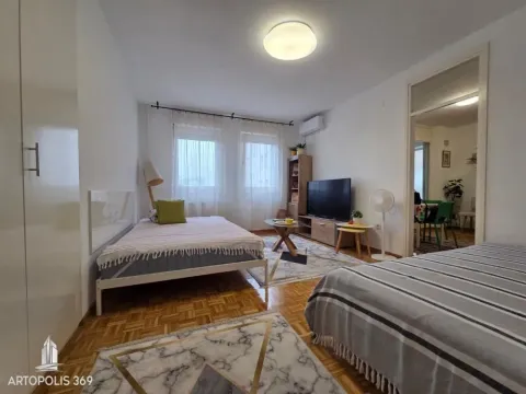 Prostrana spavaća soba sa krevetom, televizorom i pogledom na prozore. - image 7