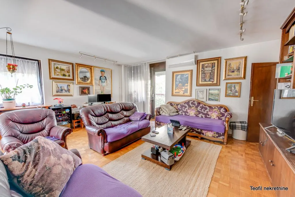Living room with a sofa set, coffee table, and numerous paintings on the wall.