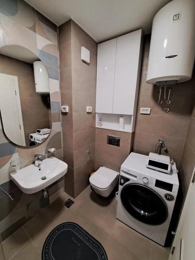 Moderno opremljeno kupatilo sa sanitarijama, tuš kabinom, umivaonikom i veš mašinom.