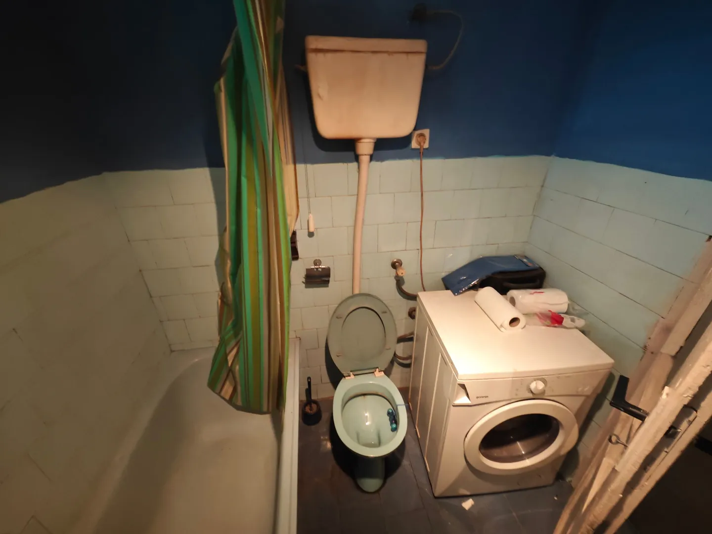 Starije kupatilo sa kadom, wc šoljom i veš mašinom.