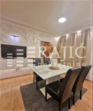 Modern dining area with a table, chairs, and TV unit. - image 3