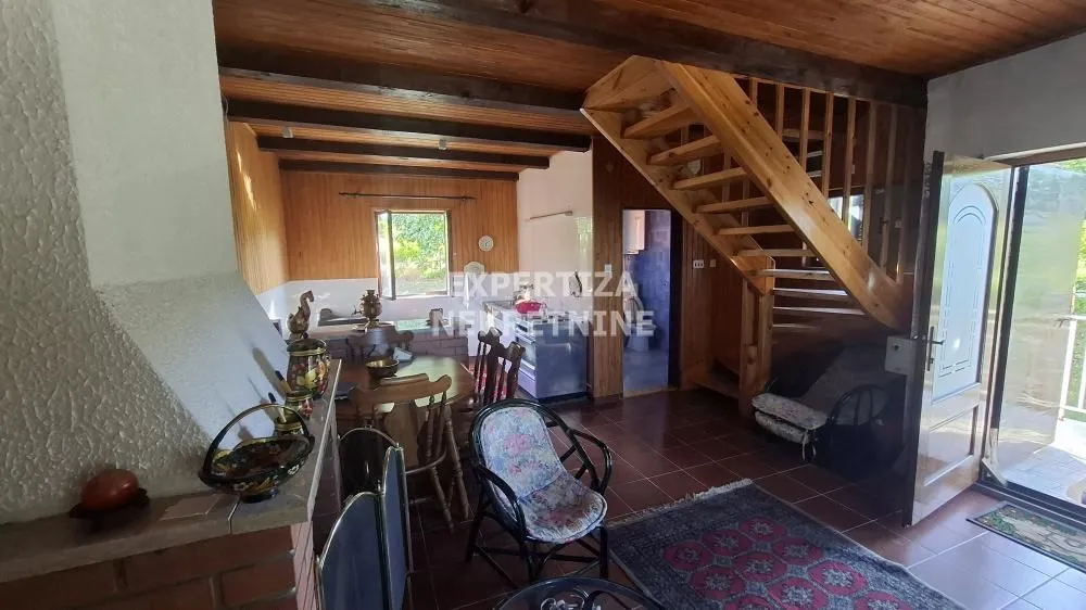 Living room with dining area and wooden staircase.