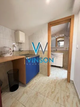 Small tiled kitchen with a view into the bathroom through the doorway. - image 6