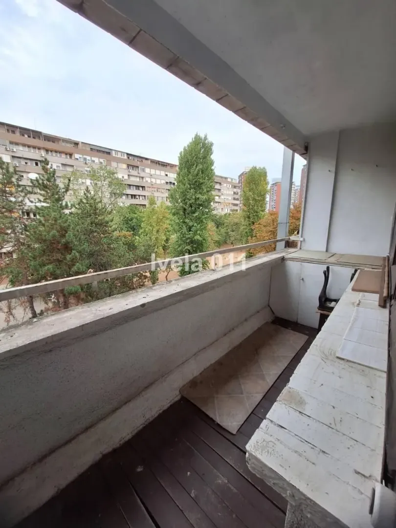 Natkriveni balkon sa pogledom na park i drveće.
