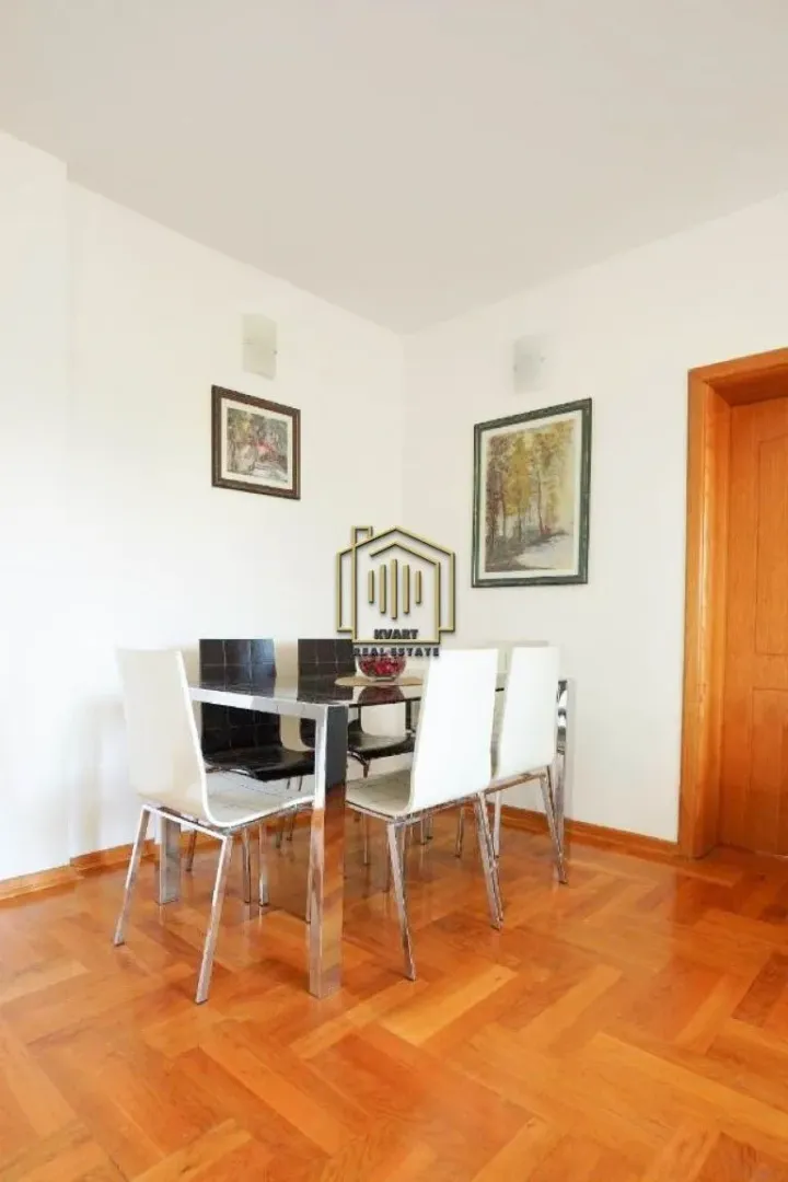 Dining area with a table, chairs, and parquet flooring.
