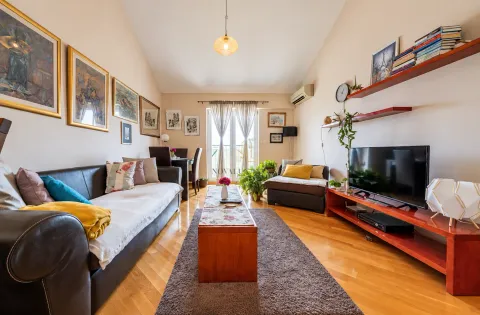 Living room with a sofa, TV, and a dining table in the background. - image 2