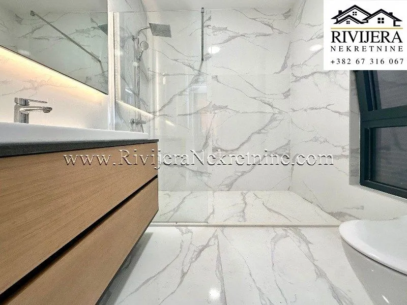 Modernly equipped bathroom with a walk-in shower and marble tiles.