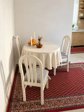 Trpezarija sa okruglim stolom, bijelim stolicama i crvenim tepihom. - image 7