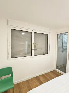 Spavaća soba sa bijelim zidovima, prozorom i vratima koja vode na terasu. - image 11