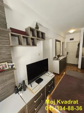 Dnevna soba sa televizorom, nameštajem i ulaznim delom u pozadini. - image 5