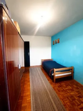 Manja spavaća soba sa krevetom, velikim drvenim ormarom i plavim zidom. - image 10
