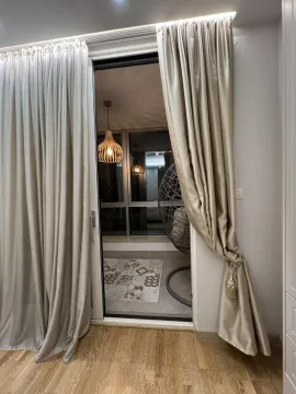 Pogled kroz balkonska vrata na uređenu terasu sa visećom foteljom. - image 2