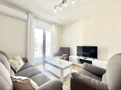 Living room furnished with a sofa set, television, and access to a balcony. - image 2