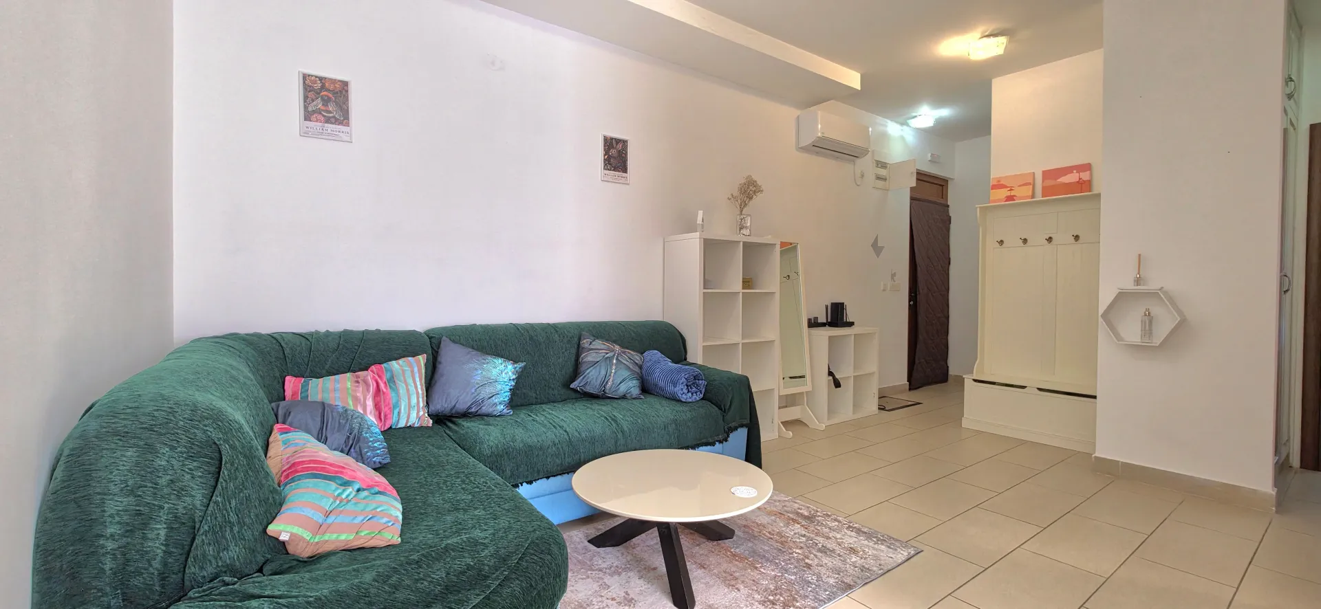 Living room with a green sectional sofa, coffee table, and shelving units.