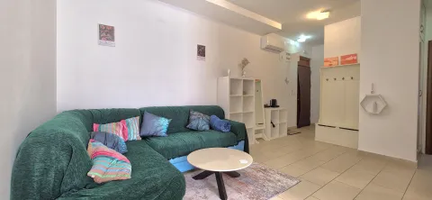Living room with a green sectional sofa, coffee table, and shelving units. - image 2