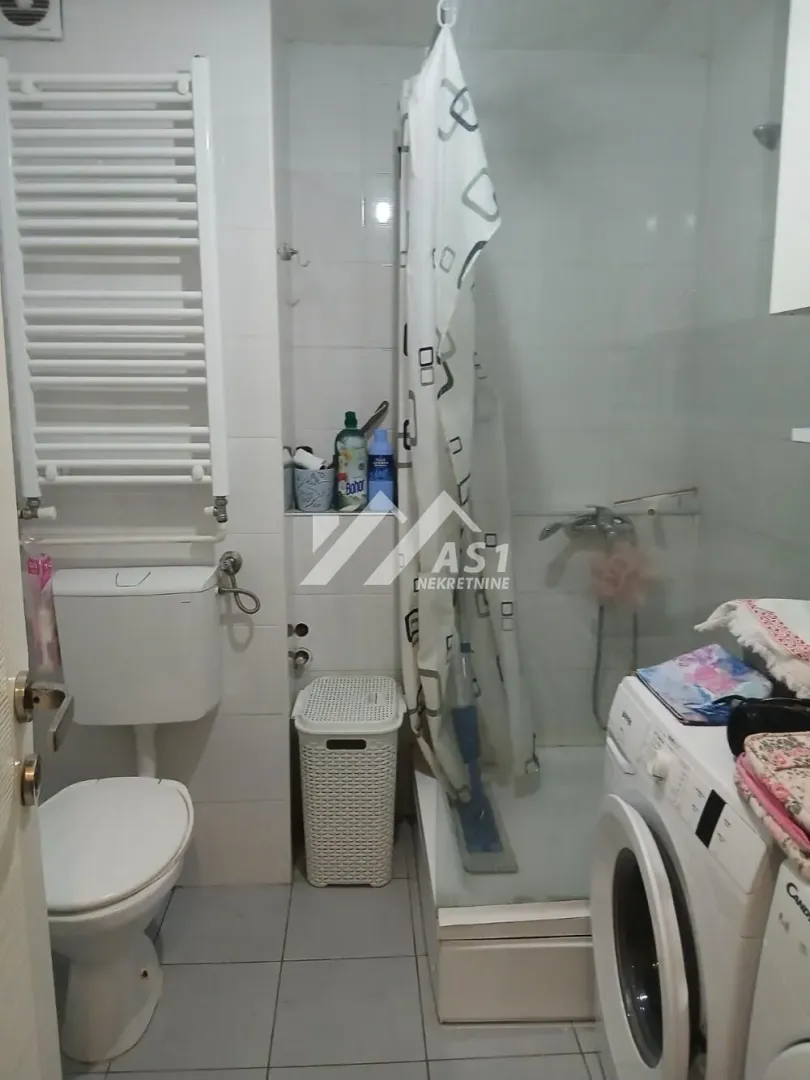 Manje kupatilo sa tuš kabinom, wc šoljom i veš mašinom.