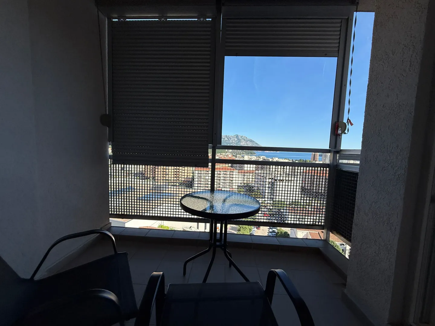 Enclosed balcony with seating furniture and views of the city and sea.
