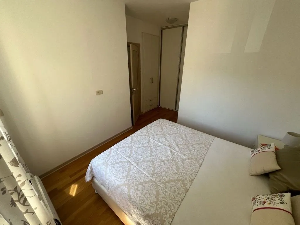 Namještena spavaća soba sa bračnim krevetom i ugradnim plakarom.