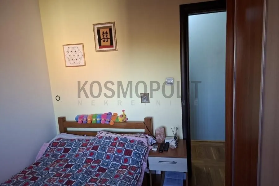 Manja spavaća soba sa bračnim krevetom i noćnim stočićem.