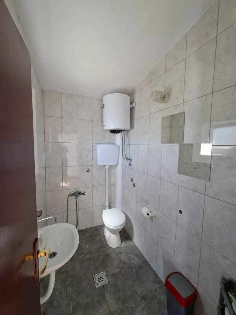 Manje kupatilo sa pločicama, wc šoljom, umivaonikom i bojlerom.