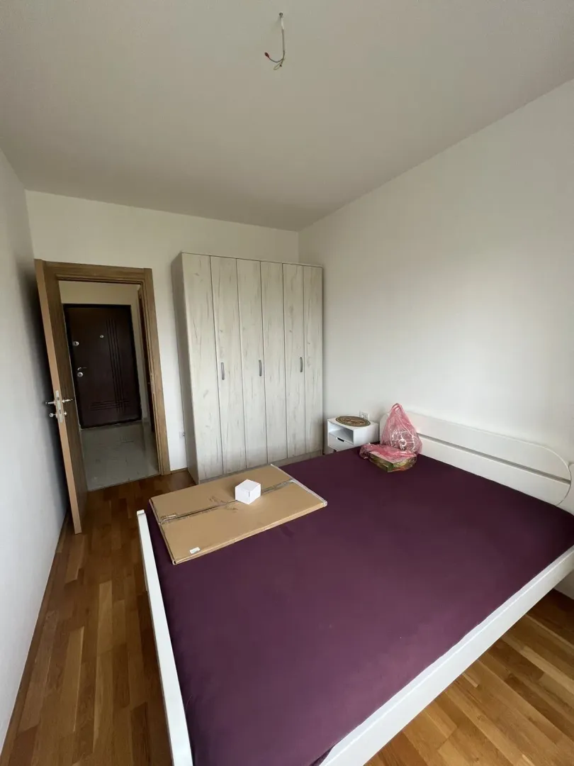 Bright bedroom featuring a double bed, a large wardrobe, and wooden flooring.