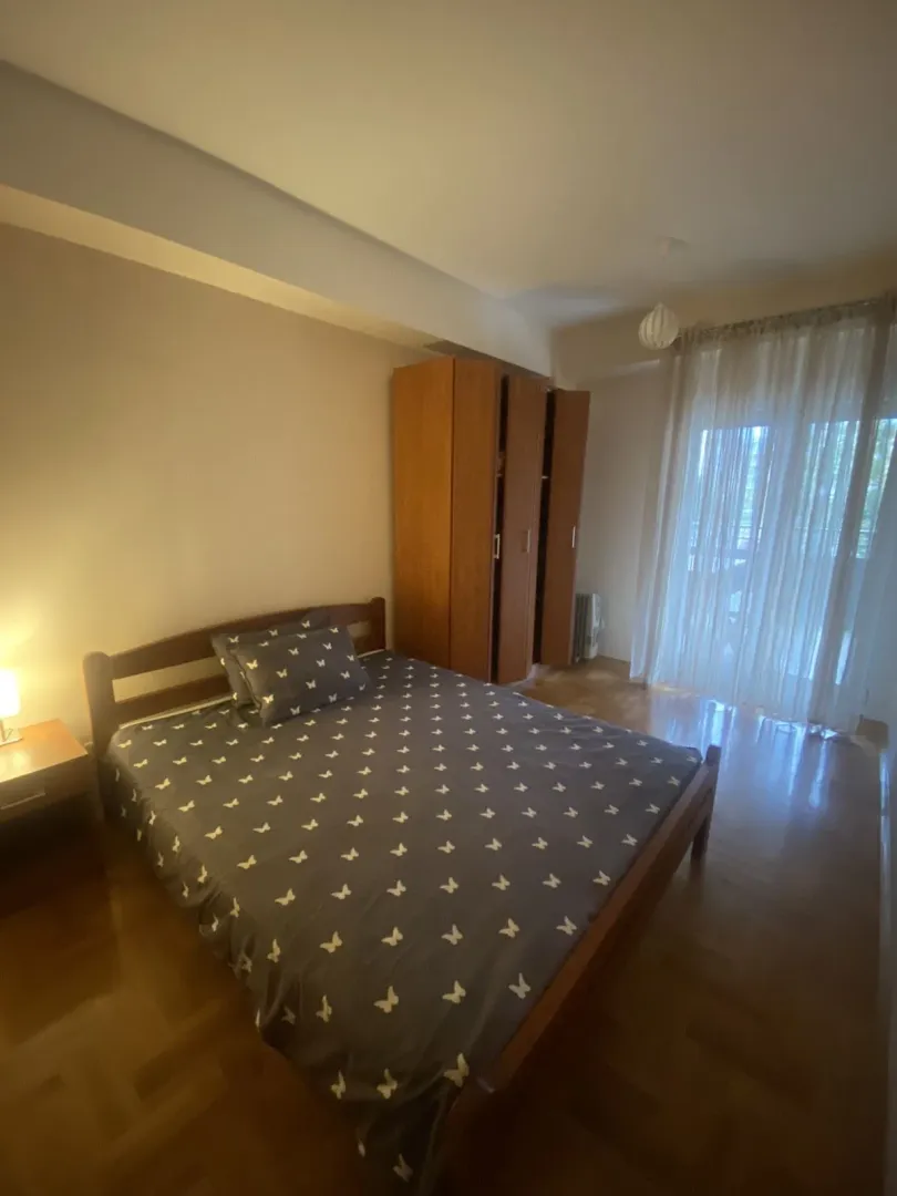 Bright bedroom with a double bed and a wooden wardrobe.
