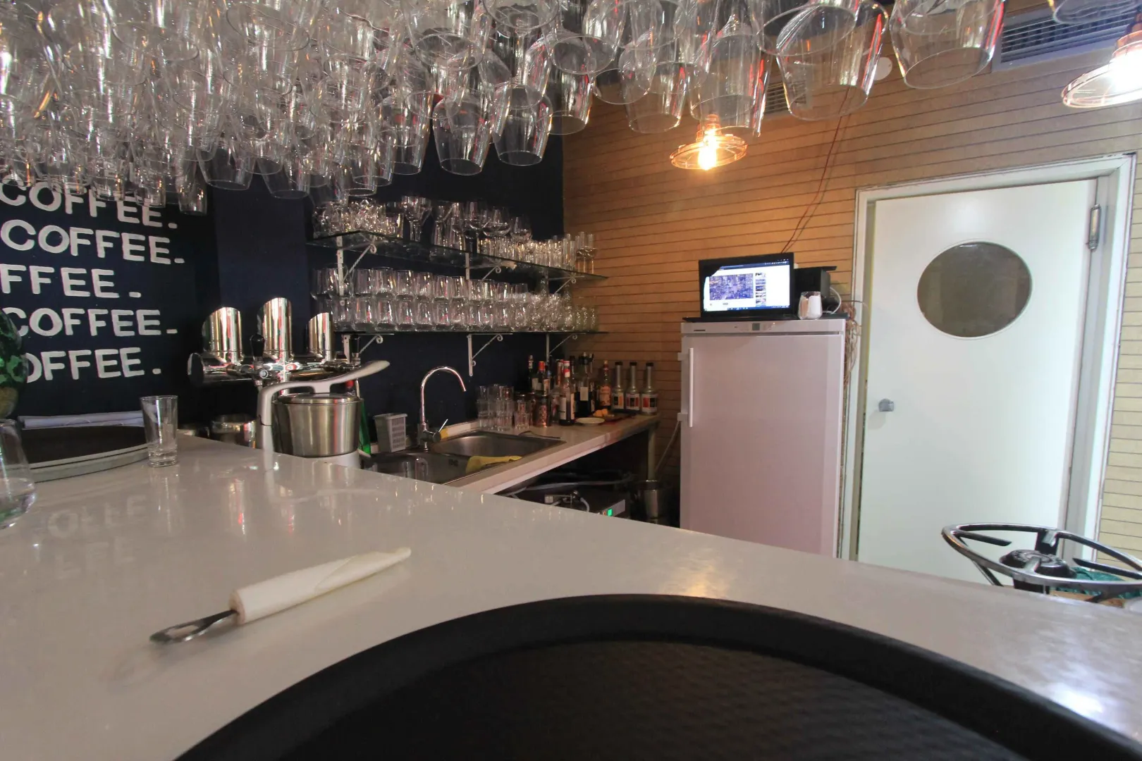 Kitchen equipped with a bar counter, sink, and shelves for glasses.