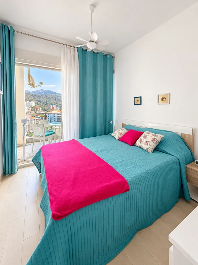 Bright bedroom with a double bed and access to a terrace with city views.