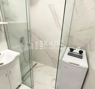 Modern bathroom with a shower cabin, washbasin, and washing machine. - image 8