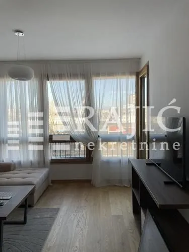 Living room with a sofa and large windows letting in plenty of light.