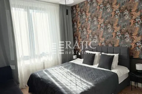 Furnished bedroom with a double bed, patterned wallpaper, and a window with curtains. - image 9