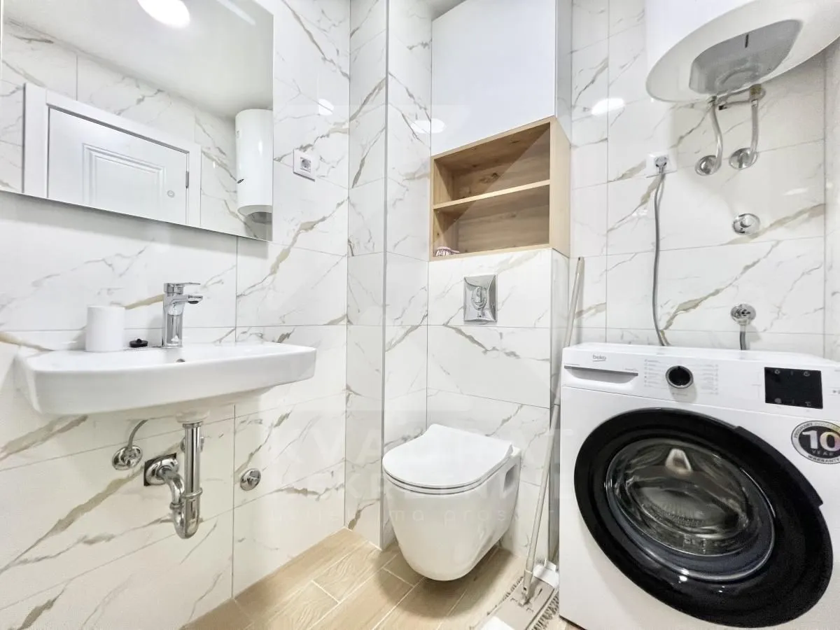 Moderno opremljeno kupatilo sa umivaonikom, WC šoljom i veš mašinom.