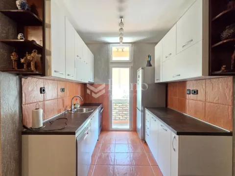 Narrow kitchen with white cabinetry and orange tiles. - image 3