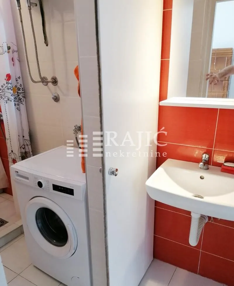 Small bathroom with a sink, shower area, and washing machine.
