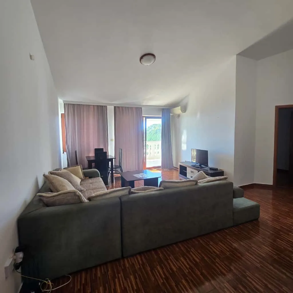 Living room with a sofa, TV, and dining area with access to the terrace.
