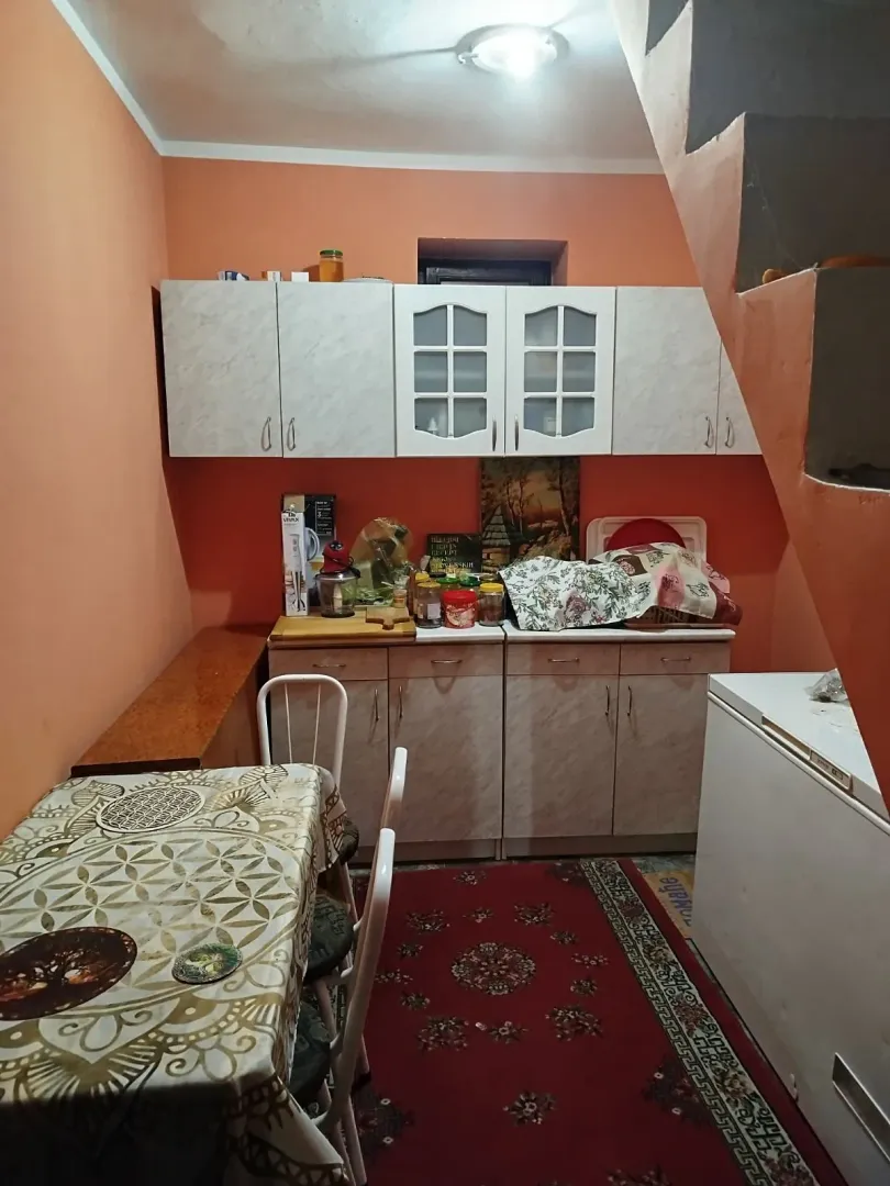 Manja kuhinja sa elementima i trpezarijskim stolom u potkrovlju.