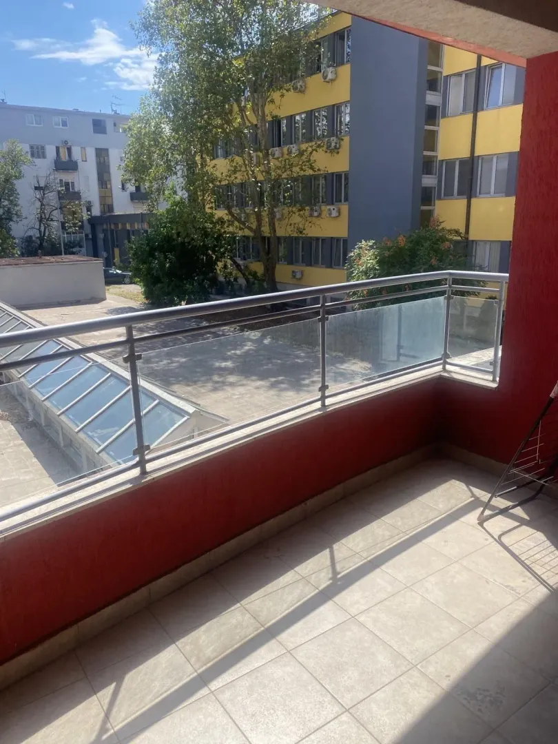 A terrace with a metal railing and a view of surrounding buildings.
