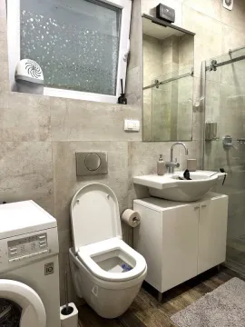 Equipped bathroom with toilet, sink, and shower cabin. - image 6