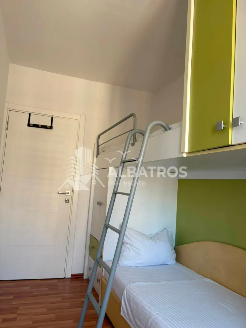 Children's bedroom with a bunk bed and green furniture elements.