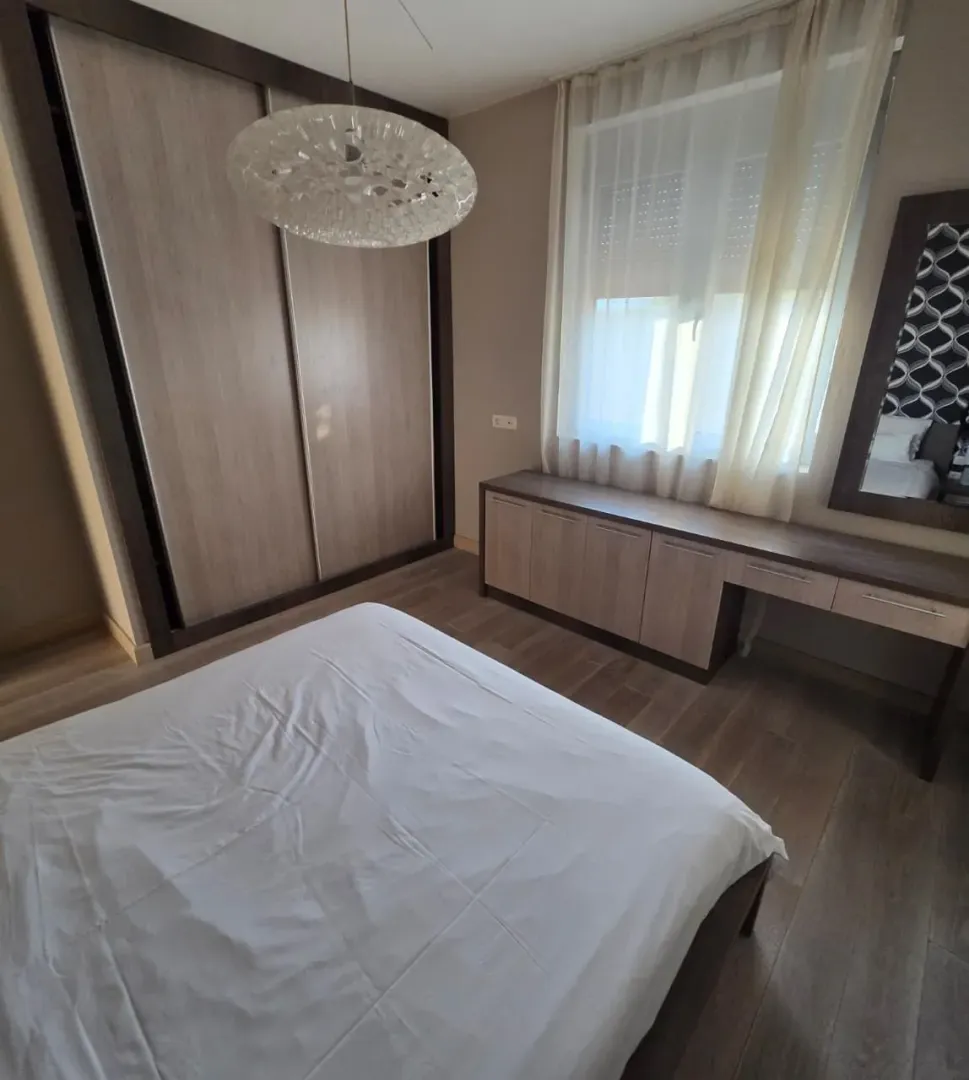 Furnished bedroom with a double bed, large wardrobe, and a desk.