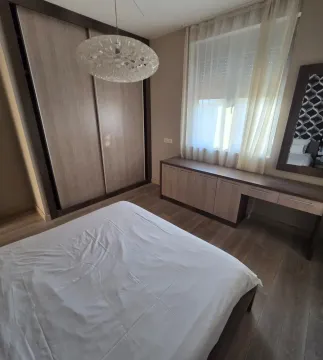 Furnished bedroom with a double bed, large wardrobe, and a desk. - image 5