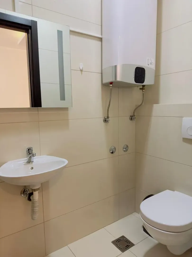 Manje kupatilo sa umivaonikom, WC šoljom, ogledalom i bojlerom.