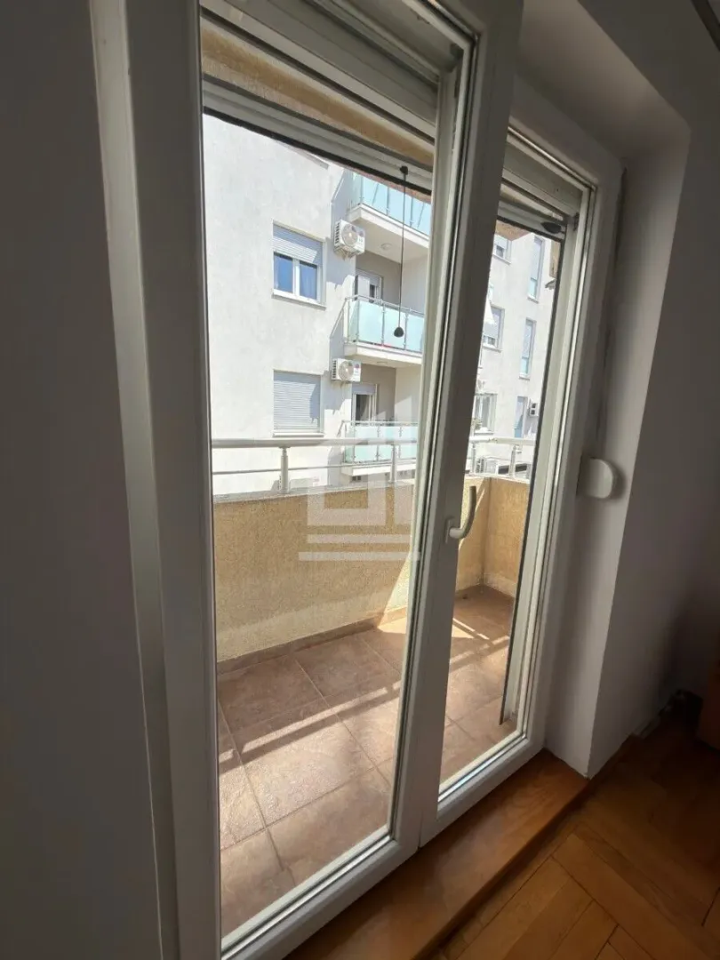 Pogled na balkon i susjedne zgrade kroz zatvorena balkonska vrata.