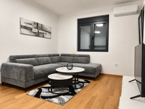 Living room with a gray sectional sofa, coffee table, and television. - image 2