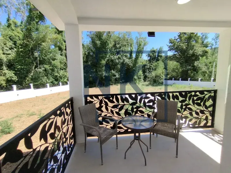 Covered terrace with seating furniture and a view of the yard and nature.