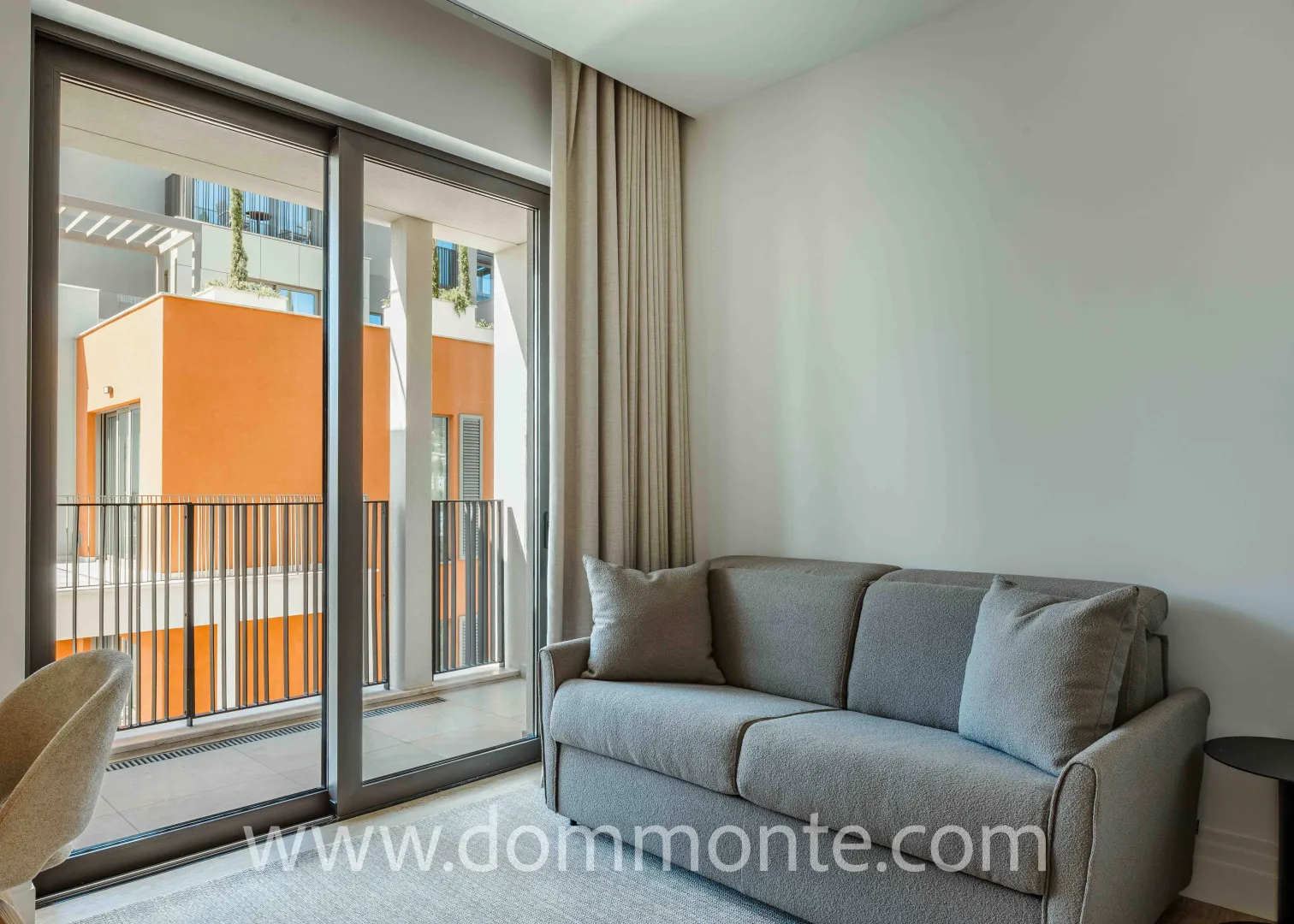 Living room with a grey sofa and large sliding doors leading to the terrace.